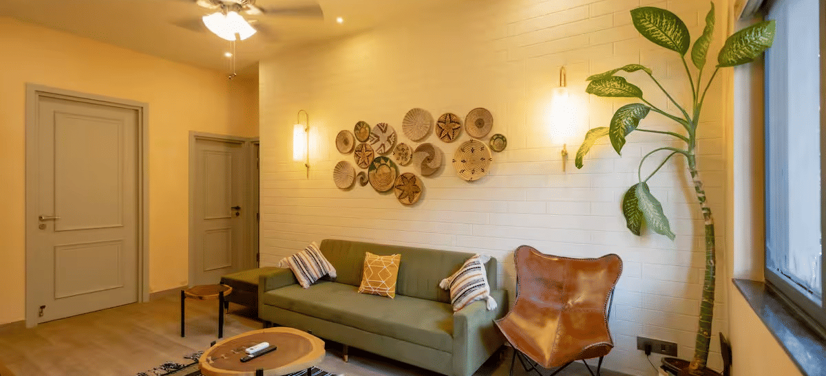 A cosy living room with a cushioned sofa, a small round table on a carpet, warm lighting, and indoor plants at Lime Tree Villa with Private Pool | Luxury Stay in Goa.